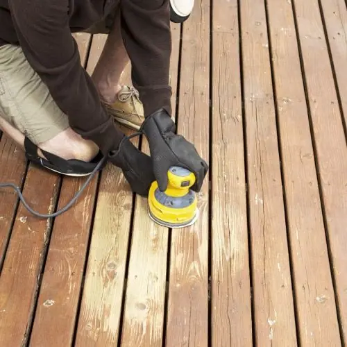 Orbital sander smoothing weathered deck boards