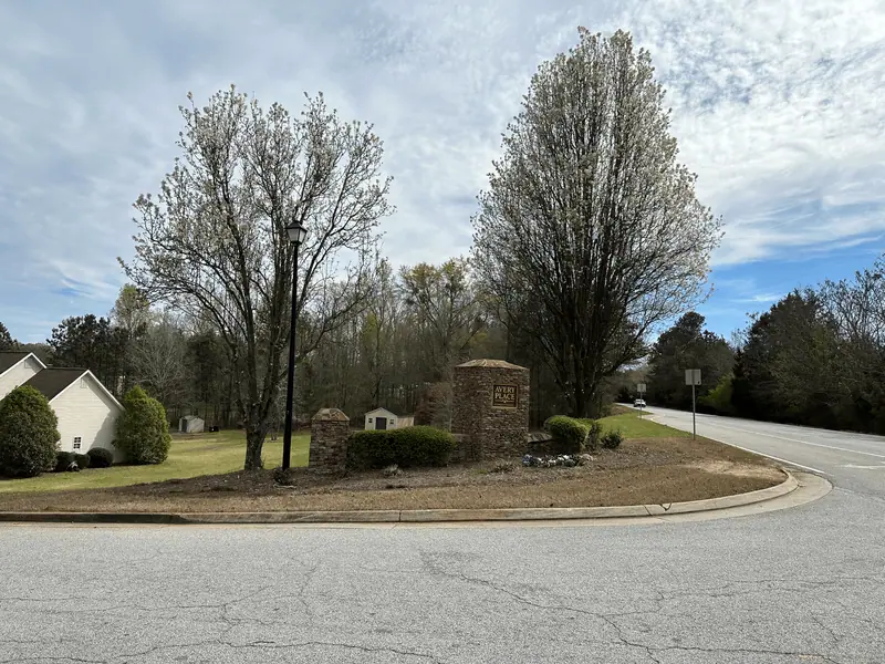 Subdivision entrance with a stone column, trimmed shrubs and mulched beds