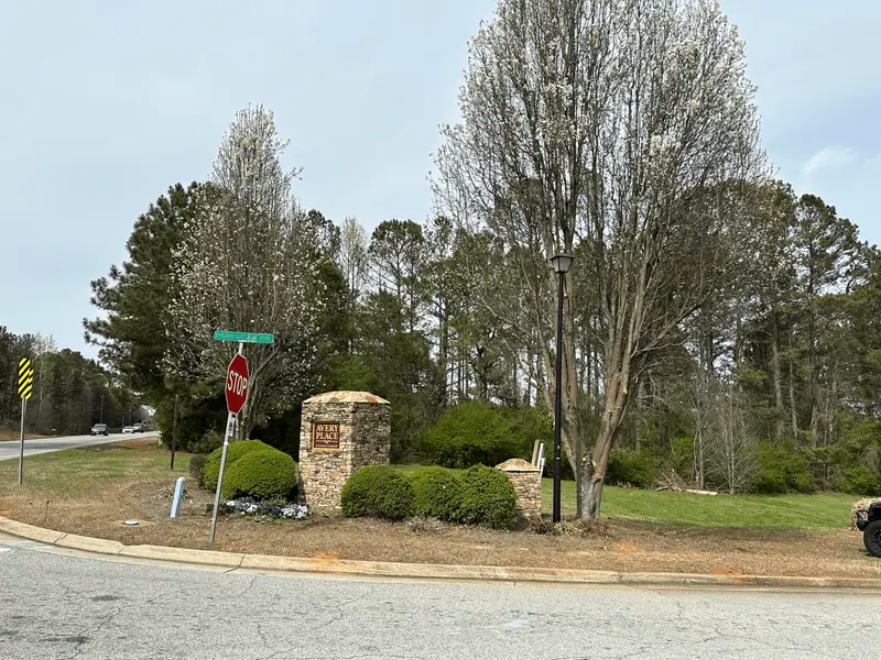 Neighborhood entrance with a stone sign column and planted beds