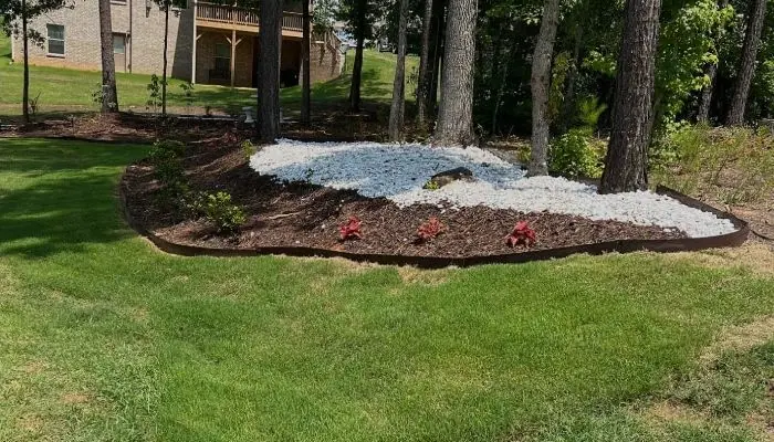 Curved bed of white stone and fresh mulch set into a green lawn