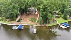 Aerial view of a wooded lakefront lot sloping down to its docks