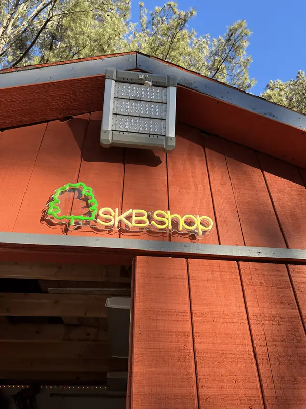 The green tree-and-SKB Shop sign lit up on the red board-and-batten shop